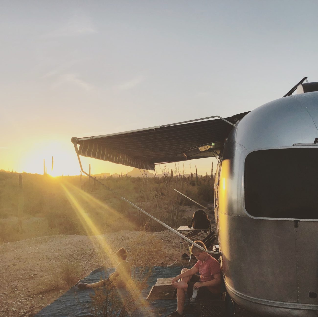Airstream at sunset in desert with awning out.