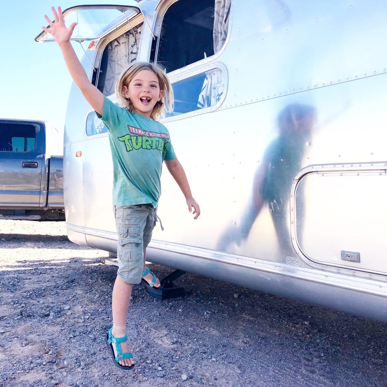 Girl jumping high five outside of Airstream