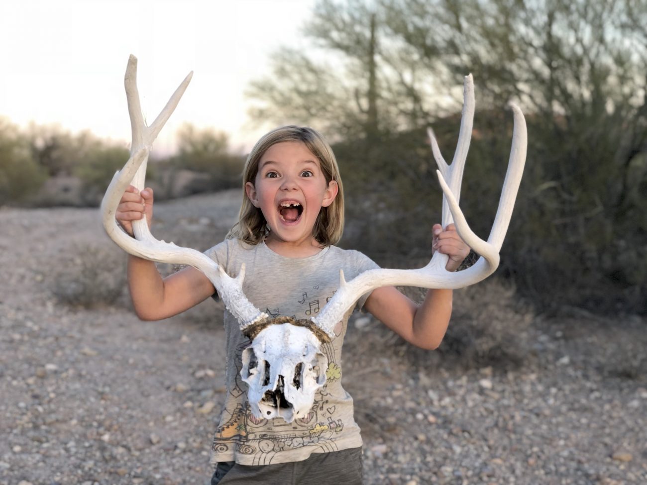 Little girl holding deer skull.