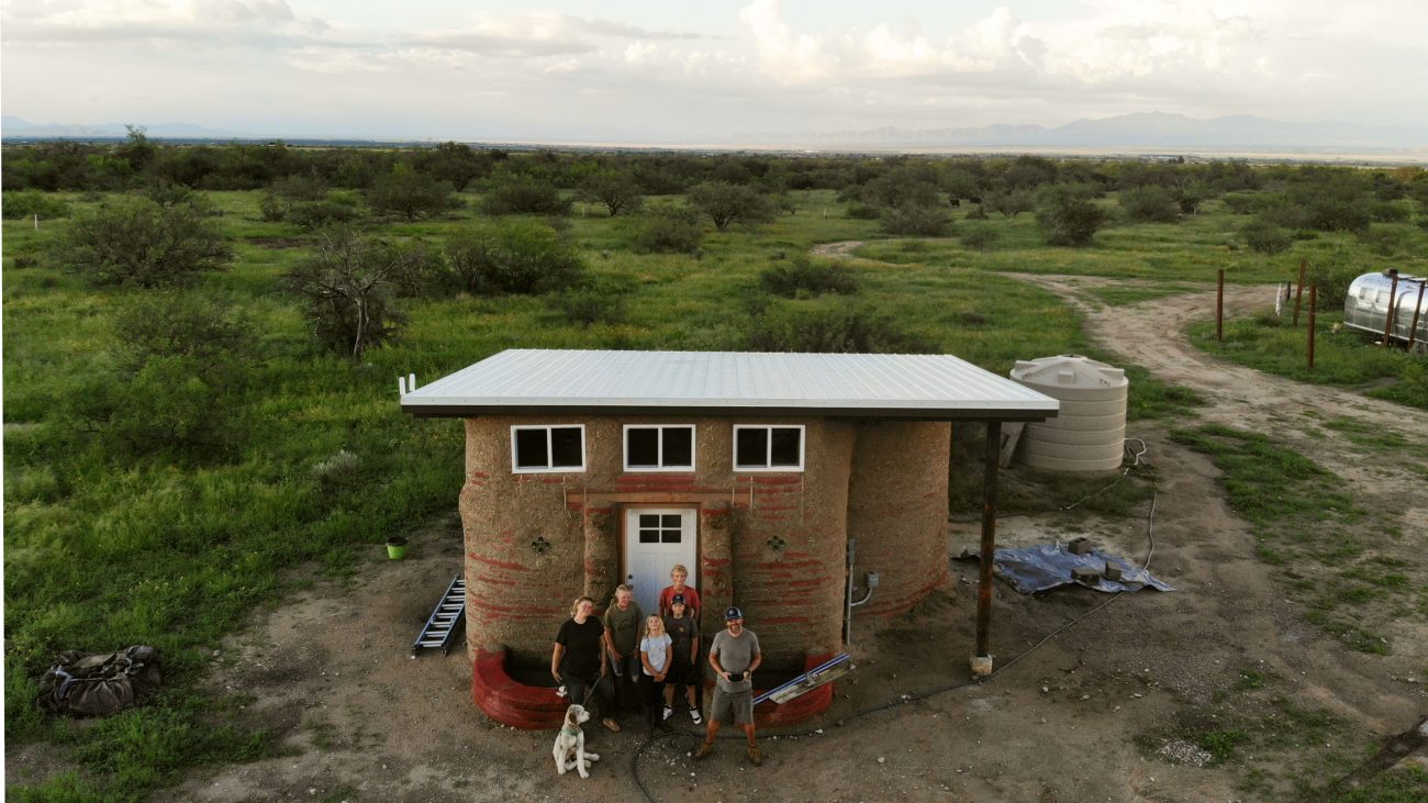 Family standing in front of earthbag building